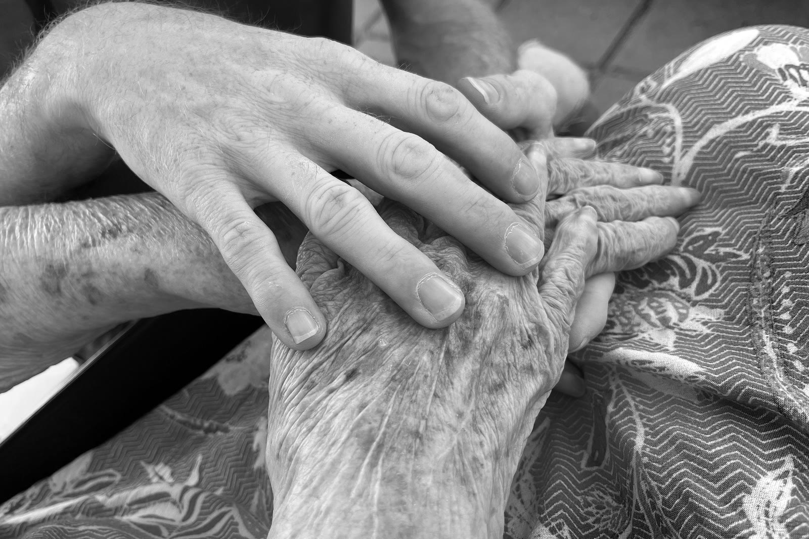 Unas manos jóvenes sosteniendo las manos de una persona mayor, en blanco y negro